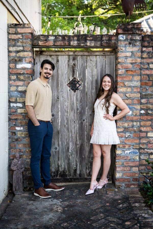 Couple in front of old wood and brick gate in Olde Town Slidell