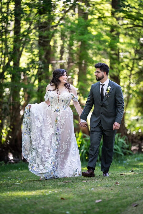 Bride and groom walk through wooded area in Slidell
