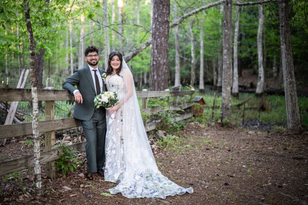 Bride and groom leaning against fence at Slidell wedding