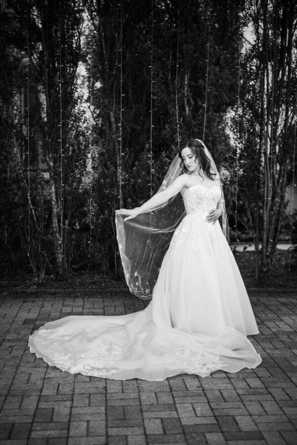 Moody black and white image of bride repositioning veil
