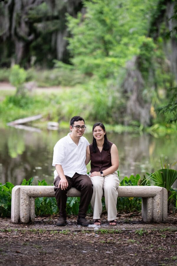 Couple sitting on concrete bench in park with lagoon in the background