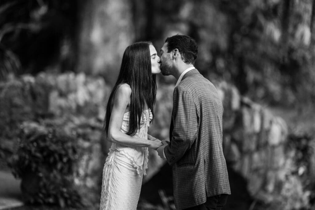 Couple kisses in front of stone bridge