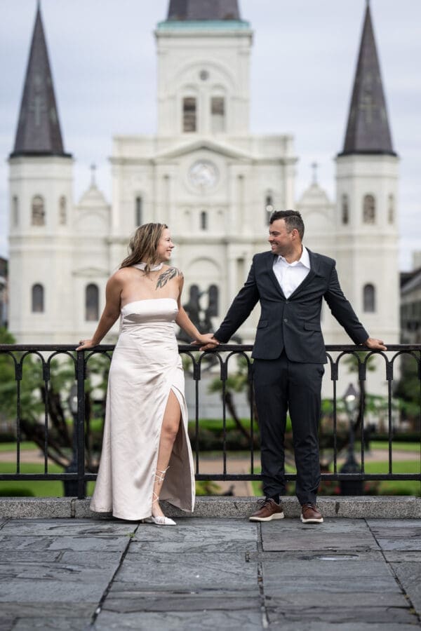 Couple leaning against railing with St. Louis Cathedral in the background
