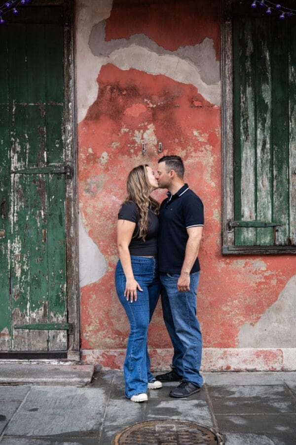 Couple kissing in front of weathered wall and shutters in the French Quarter