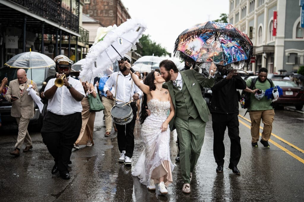 Bride and groom kiss during second line parade through the French Quarter