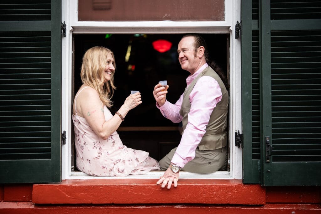 Couple sitting in window of Erin Rose bar in the French Quarter