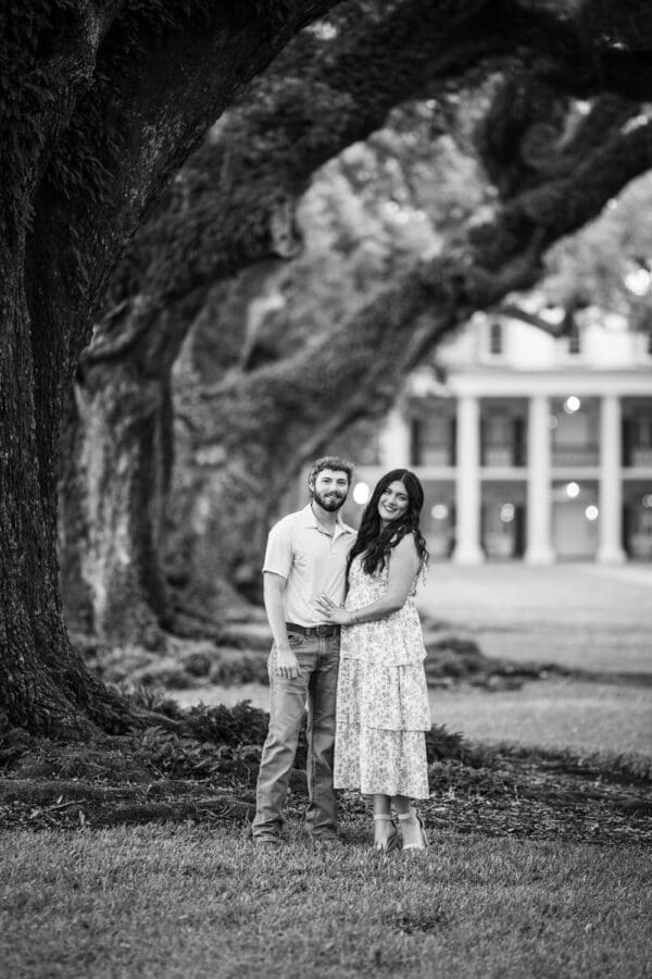 Couple standing in front of row of large trees with Oak Alley in the background