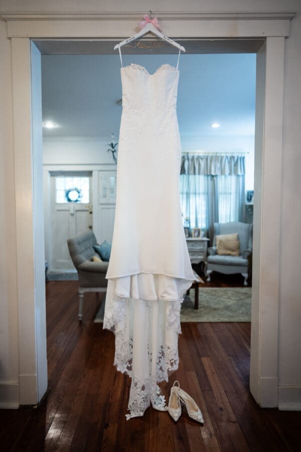 Wedding dress hanging in doorway with shoes on floor