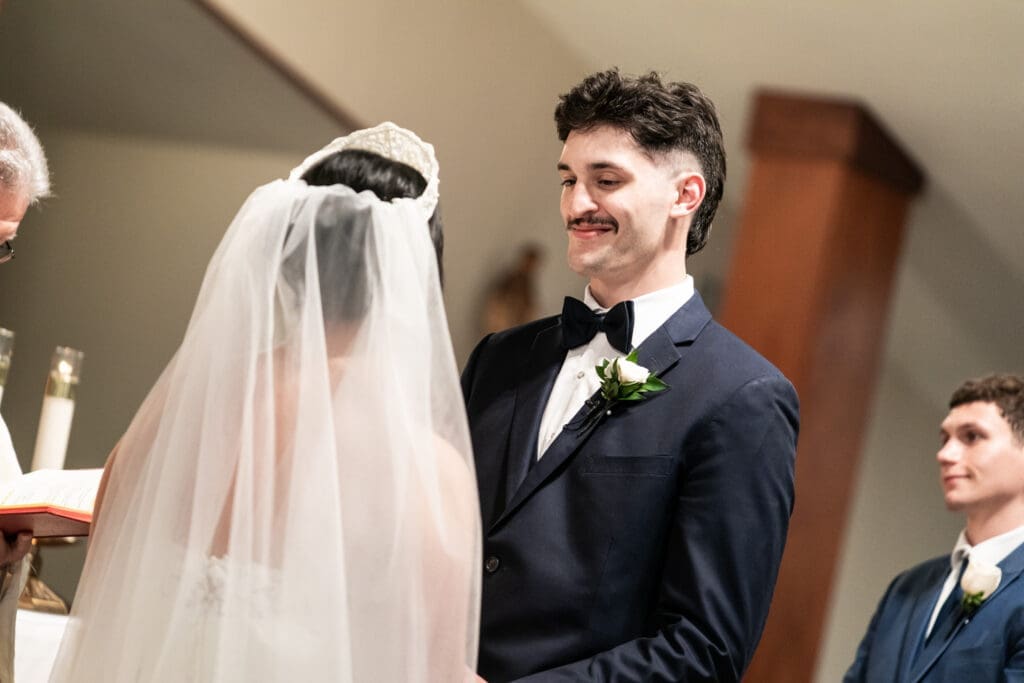 Groom smiles at bride during vows