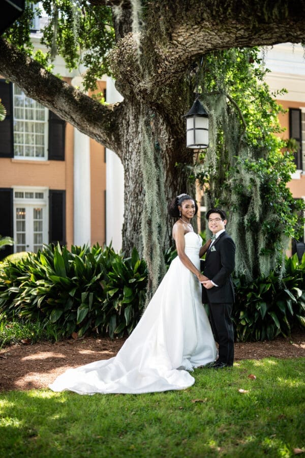 Bride and groom standing in front of large oak tree