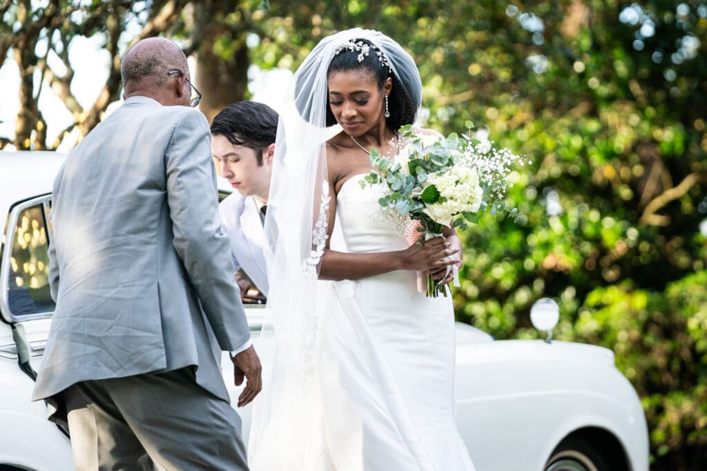 Bride exits antique Rolls-Royce at beginning of wedding ceremony