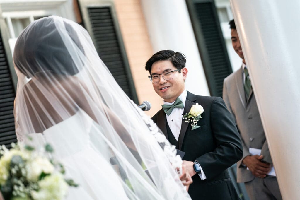Groom smiles as bride reads vows