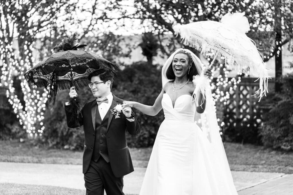 Bride and groom celebrate as they walk up the aisle holding umbrellas