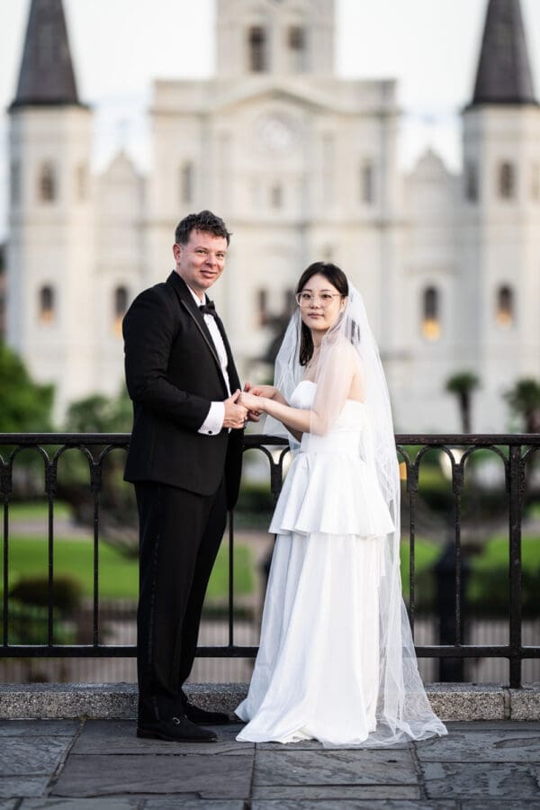 Couple standing in front of wrought iron railing with St. Louis Cathedral in the background