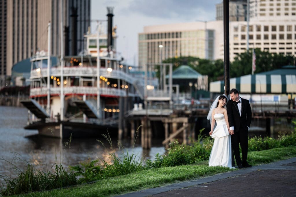 Couple holding hands on New Orleans riverfront with steamboat Natchez in the background
