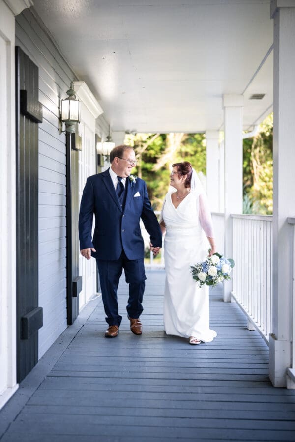 Bride and groom walking along porch of Antebellum House in Slidell