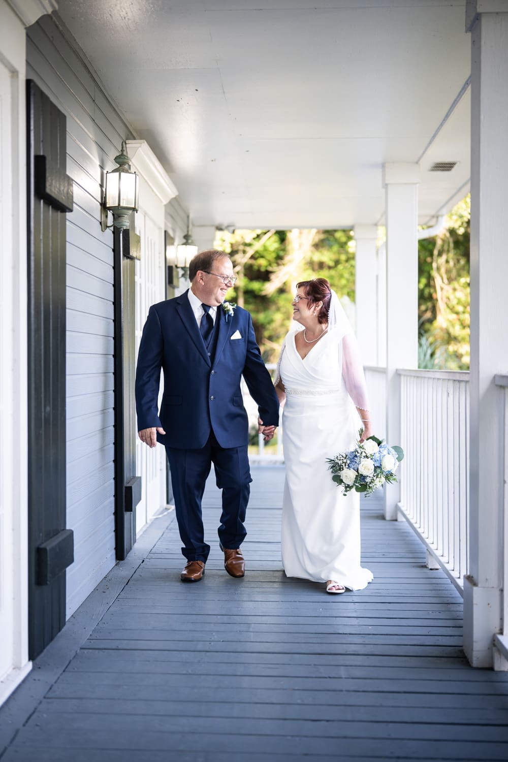 Bride and groom walking along porch of Antebellum House in Slidell
