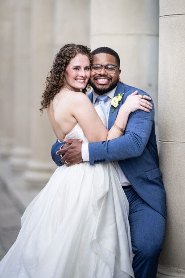 Bride and groom hug in front of large columns