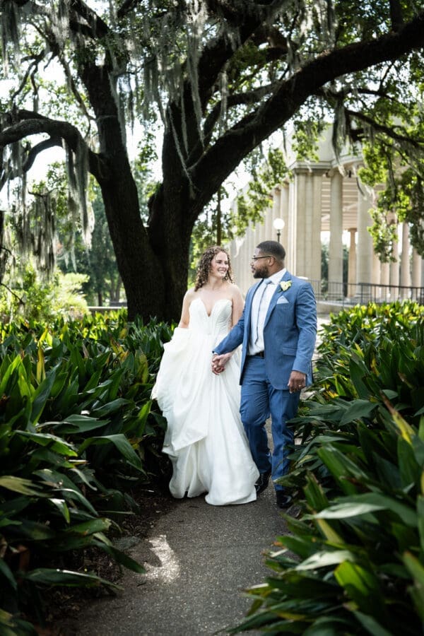 Bride and groom walk down pathway in park