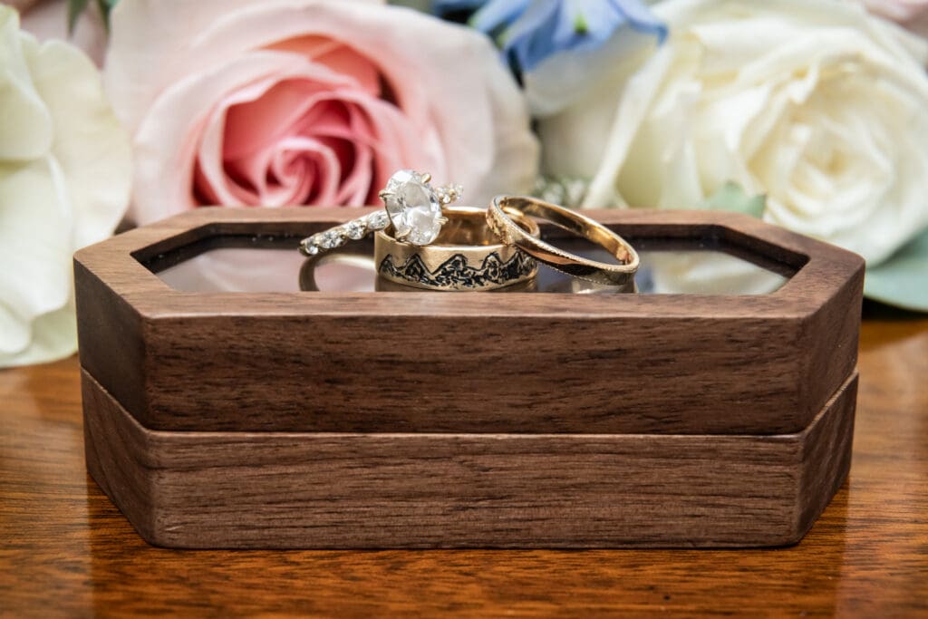 Wedding rings on box with flowers in the background