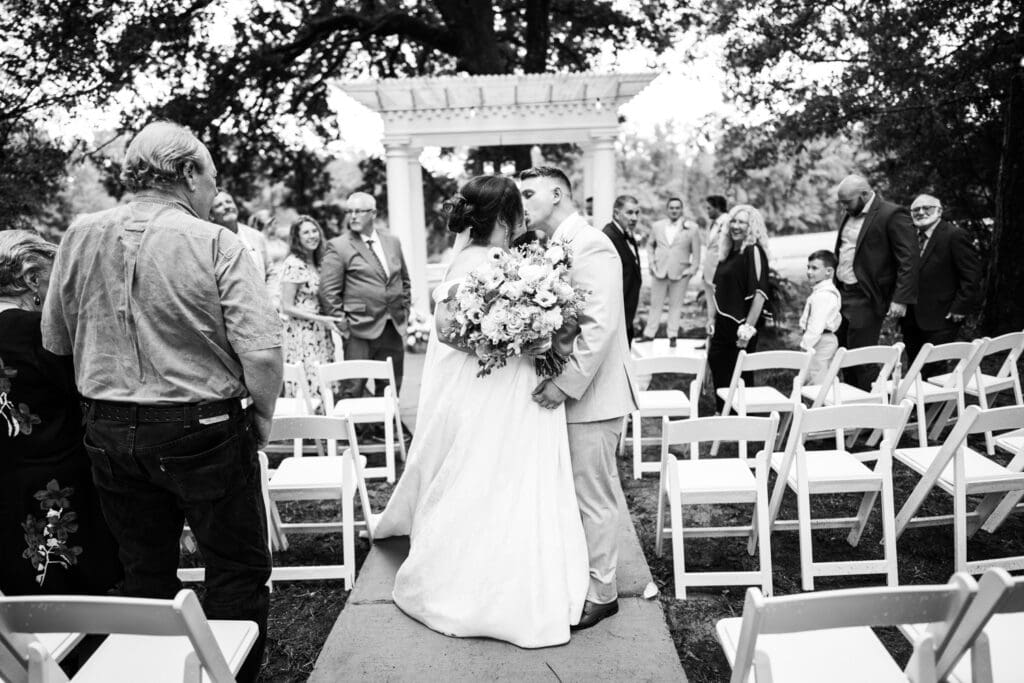 Bride and groom kiss in the aisle at The Homestead in Carriere, MS
