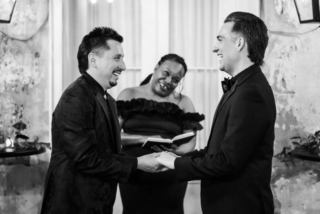 Two grooms laugh during wedding ceremony
