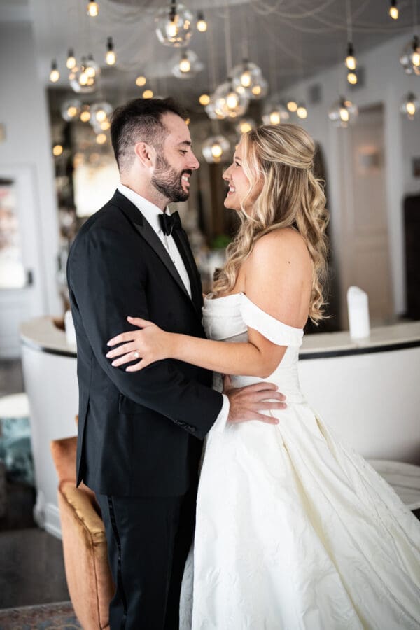 Bride and groom embrace with light globes in the background
