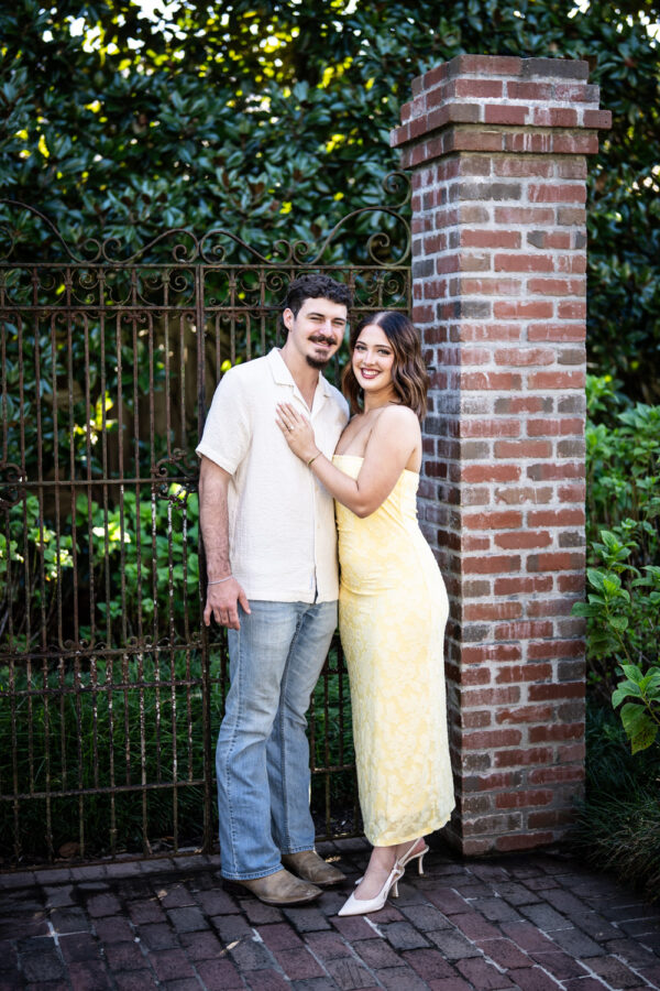 Couple standing in front of old gate and brick column