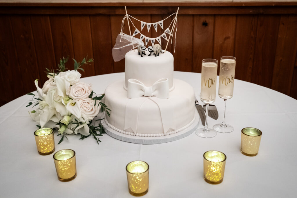 Small wedding cake on table with flowers, candles, and bouqet